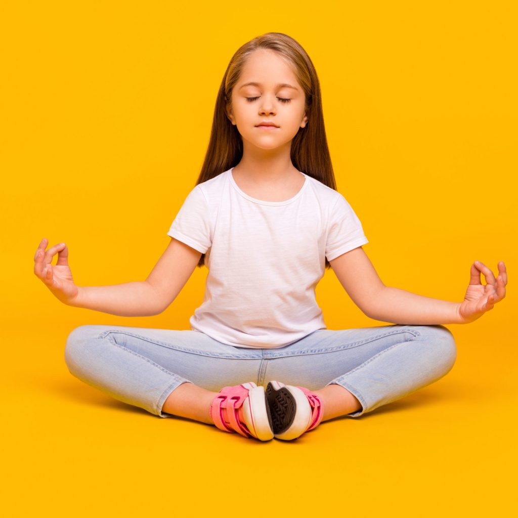 Full length photo of funny dreamy schoolgirl dressed white t-shirt sitting floor practicing yoga isolated yellow color background.